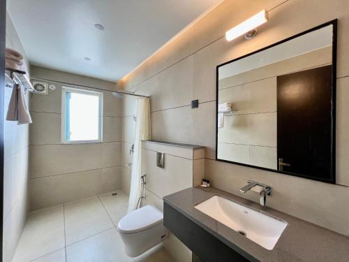 a bathroom with a sink and a toilet and a mirror at Hotel Mango Groves in Kotdwāra