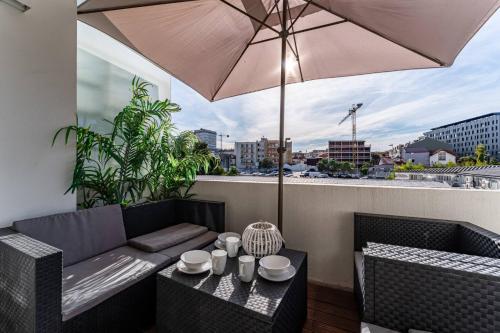 a patio with a table and an umbrella on a balcony at Brittos Avenue Apartment in Gaia in Vila Nova de Gaia