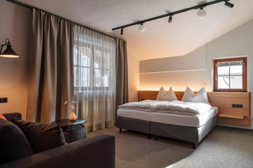 a bedroom with a bed and a couch and a window at Julius Appartements & Zimmer in Wagrain