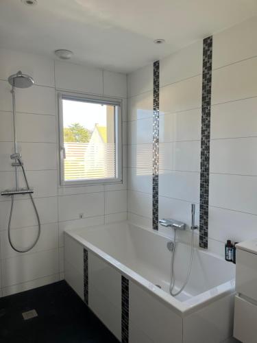 a white bathroom with a tub and a window at Amélia HOST chambre climatisée in Saint-Rémy-lès-Chevreuse