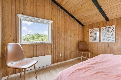 a bedroom with two chairs and a bed and a window at 6606-Hvide-Sande-Arvidvej-164 in Bjerregård