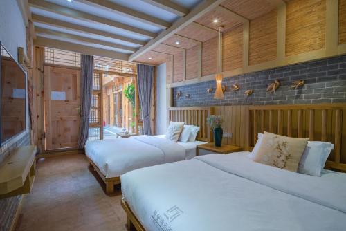 a hotel room with two beds and a window at Sunlit Snow Mountain Z Naxi Ethnic Style Courtyard in Lijiang