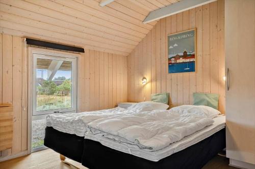 a large bed in a room with a window at 3395-Hvide-Sande-Fyrmarken-33 in Hvide Sande
