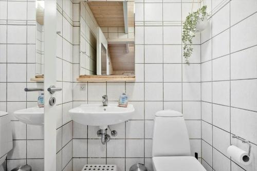 a white bathroom with a toilet and a sink at 3395-Hvide-Sande-Fyrmarken-33 in Hvide Sande