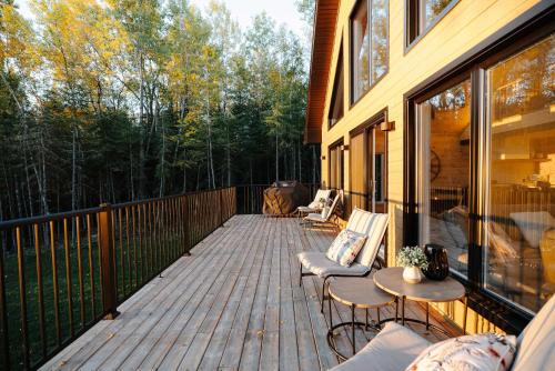 a deck with chairs and tables on a house at Chalet Le Solem Golf et Spa in Saint-Faustin