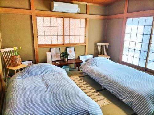 two beds in a room with two windows at さくらVillaCOAST in Futtsu