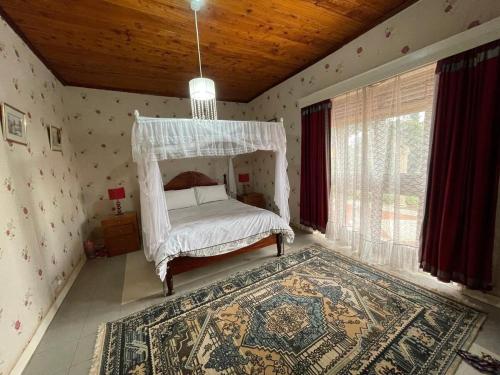 a bedroom with a canopy bed and a rug at Angel's place in Kabale
