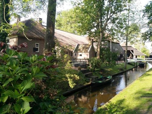 a house on a river with a boat in the water at De Kazerne - Kiersche wijde in Wanneperveen