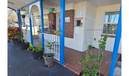 a porch of a building with potted plants on it at Holiday Motel Ocala Downtown I-75 in Ocala