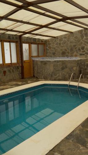 a swimming pool in a house with a stone wall at Casa rural Cristina- Piscina climatizada in Málaga