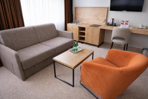 a living room with a couch and a table and chairs at Hotel Kudowa Manufaktura Relaksu in Kudowa-Zdrój