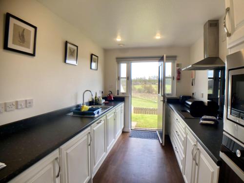 a kitchen with black counter tops and a window at Calluna Cottage in Aviemore