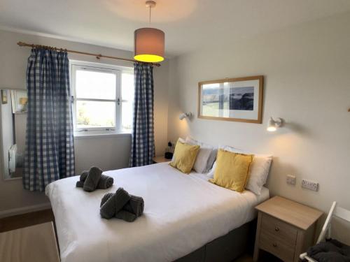 a bedroom with a large white bed with yellow pillows at Calluna Cottage in Aviemore
