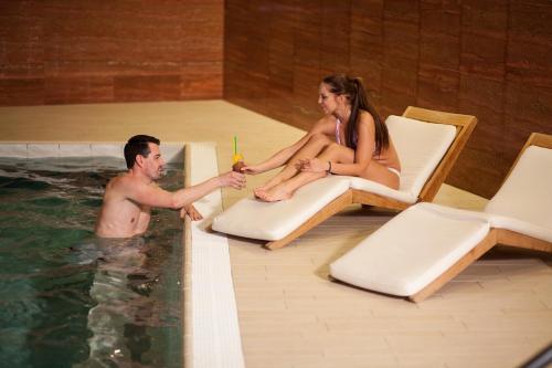 a man and a woman sitting in a swimming pool at Grund Resort Golf and Ski in Mladé Buky