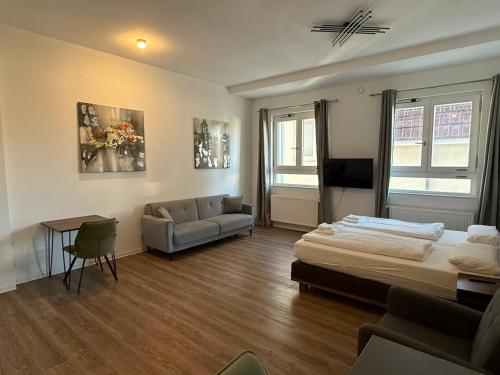 a bedroom with a bed and a couch and a tv at TRUST Boardinghouse in Stuttgart