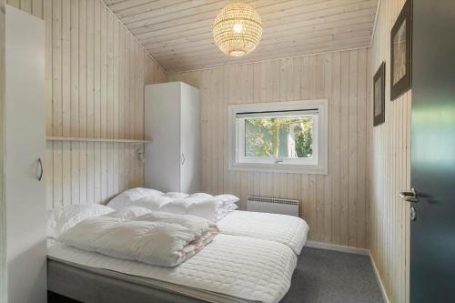 a bedroom with a bed with white sheets and a window at 1080-Stege-Berberisvej-48 in Stege