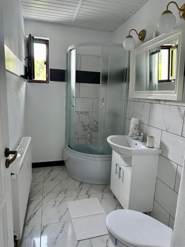 a white bathroom with a shower and a sink at MurMur Chalet in Breaza