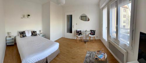 a white bedroom with a bed and a table at Studio cosy à Molsheim Calme, centre-ville et accès Strasbourg in Molsheim