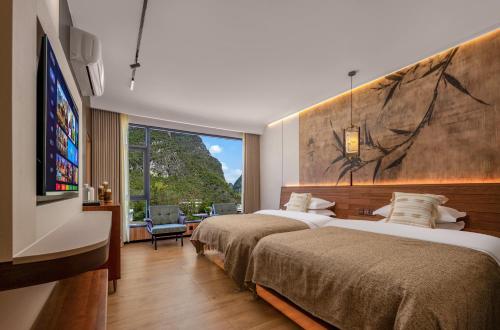 a hotel room with two beds and a large window at Meadowscape Resort at Yulong River - Karst Views & Infinity Pool & Tickets Reservation Service & Free Laundry in Yangshuo