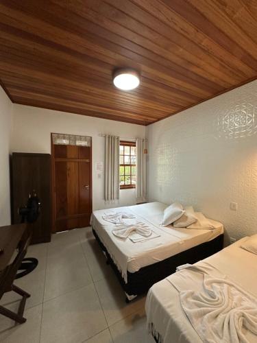 a bedroom with two beds and a wooden ceiling at Chalé Vila Catarina in Ouro Preto
