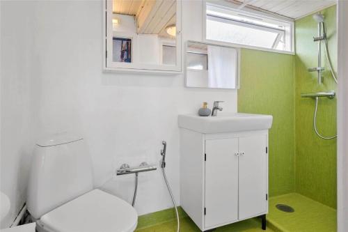 a bathroom with a white toilet and a sink at S705-Stroby-Hybenvej-1 in Strøby