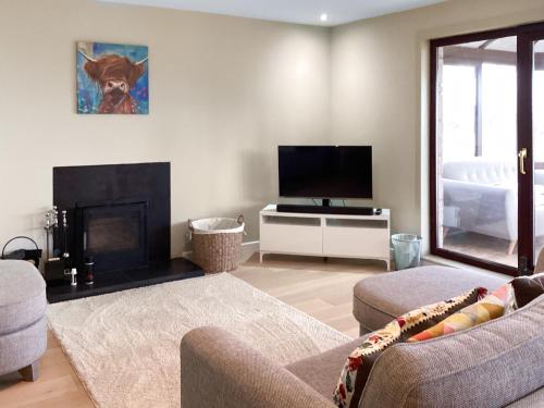 a living room with a fireplace and a tv at Stroma in Edderton