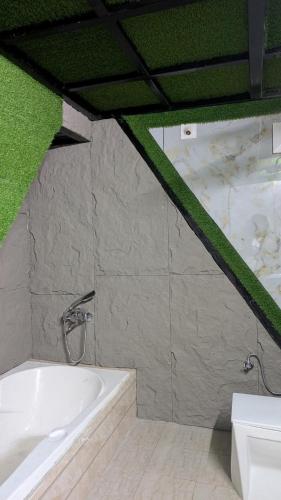 a white bath tub in a room with green moss at Kasol A-Frame Cottage in Kasol