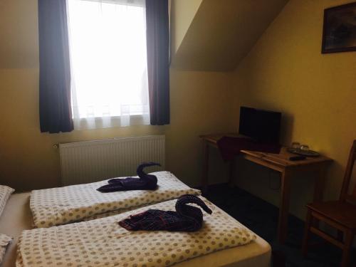 two swans are sitting on two beds in a room at Kék Lagúna Panzió in Dombrád