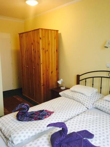 a bedroom with two beds and a wooden cabinet at Kék Lagúna Panzió in Dombrád