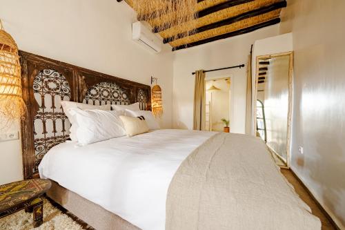 a bedroom with a large white bed with a wooden headboard at Riad Taww'Ami in Marrakesh