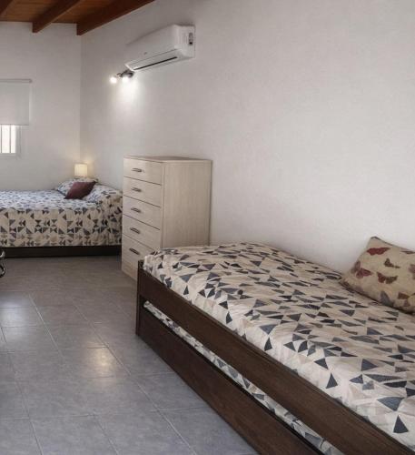 a bedroom with two beds and a dresser in it at Gotas de Rocío - para 4 en San Antonio Oeste in San Antonio Oeste
