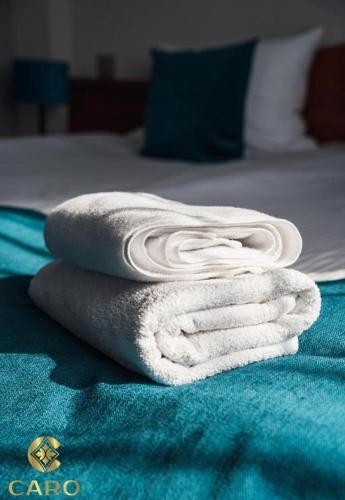 a pile of towels sitting on top of a bed at Gościniec CARO in Poznań