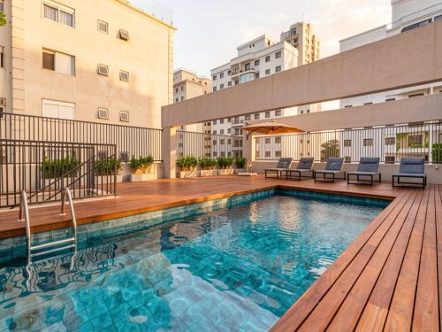 a swimming pool with a wooden deck on a building at Xtay Vila Madalena - Stay close to everything with an outdoor pool and access to the best coworking spaces in Vila Madalena in São Paulo