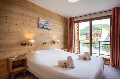 a bedroom with a large bed and a large window at Résidence Daria-I Nor by les Etincelles in L'Alpe-d'Huez
