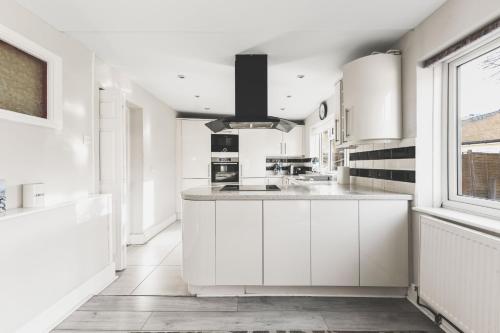 a kitchen with white cabinets and a large window at Spacious 4BDR House with Parking by Heathrow in Hillingdon