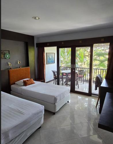 a bedroom with two beds and a balcony with a table at Green Cocoon at Bali beach in Sanur