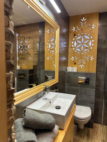 a bathroom with a sink and a toilet and a mirror at Domki Pod Góralskim Niebem in Zakopane