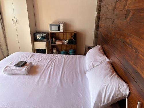 a bedroom with a white bed with a wooden headboard at Blue Moon Cozy Poolside Bachelor Flat in Bellville