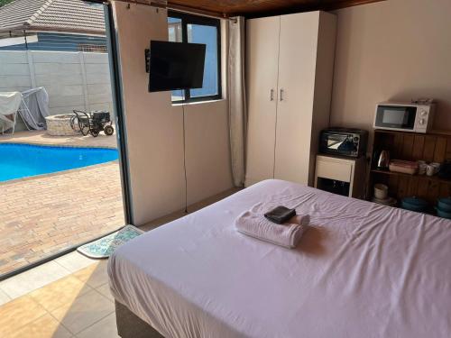 a bedroom with a bed and a tv and a pool at Blue Moon Cozy Poolside Bachelor Flat in Bellville