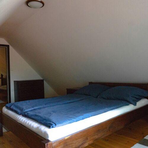 a bedroom with a bed with a blue blanket at Feketebács Nyaralóház in Káptalantóti