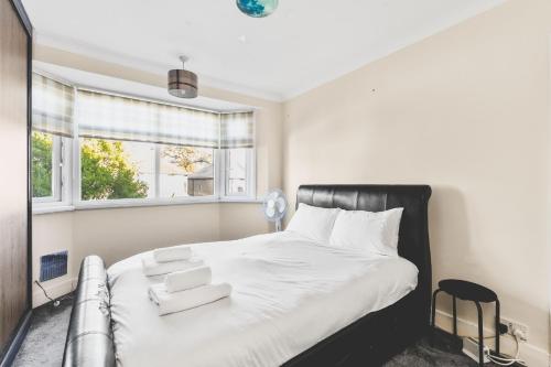 a bedroom with a large white bed with a window at Spacious 4BDR House with Parking by Heathrow in Hillingdon