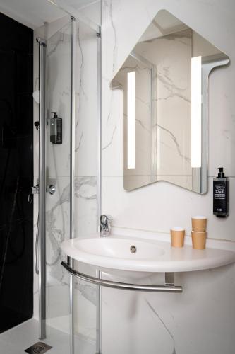 a white bathroom with a sink and a mirror at Ibis budget Périgueux in Périgueux