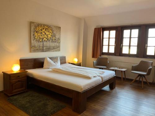 ein Schlafzimmer mit einem Bett und zwei Stühlen in der Unterkunft Hotel Weingärtner in Mannheim
