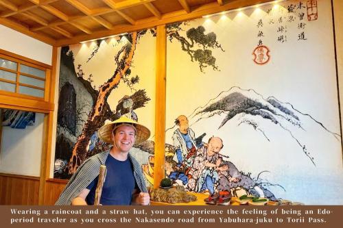 a man standing in front of a wall with a painting at Japanese Style Hotel WAKUWAKU-BASE Nakasendo Yabuharajuku