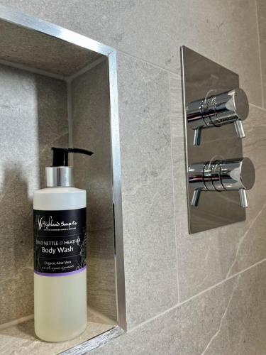 a bottle of body wash sitting on a shelf in a bathroom at Silver Birch Cottage in Aviemore