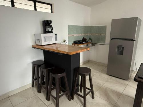 a kitchen with a counter with a microwave and stools at Loft zona centro La Merced in San Cristóbal de Las Casas
