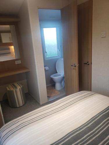 a bathroom with a toilet and a bed in a room at Lapwing 26 in Scratby