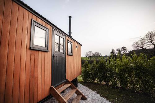 a wooden house with a bench next to it at Shepherds View in Ashbourne