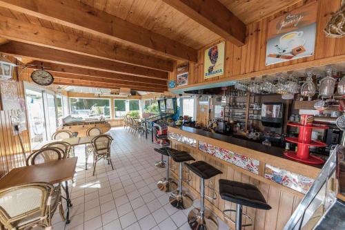 a restaurant with a bar with chairs and tables at Camping Paradis les Capucines in Trédrez