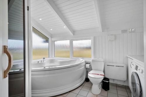a white bathroom with a tub and a toilet at 313-Harboore-Fourmivej-68 in Harboør